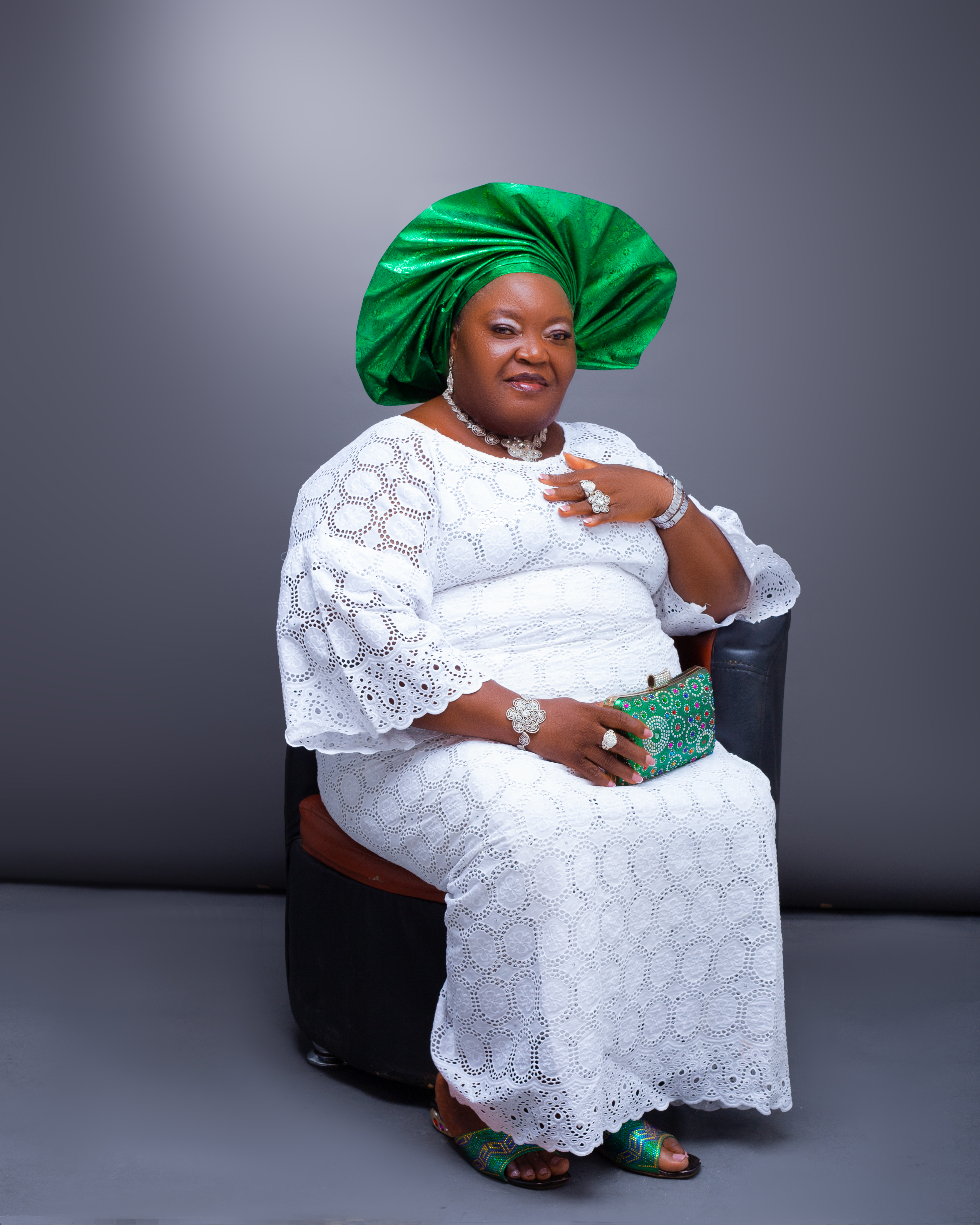 Mrs. Catherine seated in white lace outfit with green headwrap
